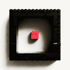 One red brick alone inside a black brick frame, with room to spare on every side.